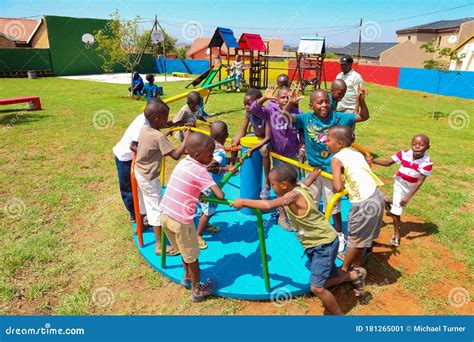 African Kids Playing Merry Go Round And Other Park Equipment At Local