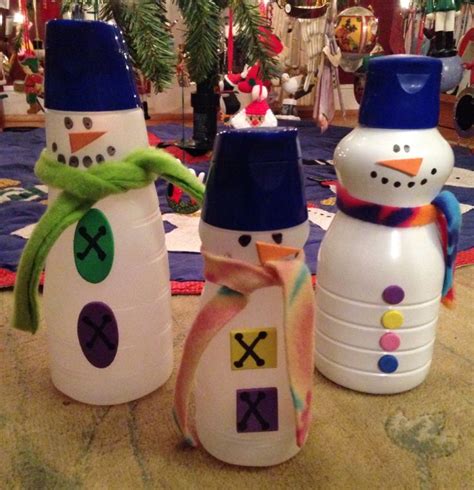 Three Snowmen Made Out Of Plastic Bottles Sitting On The Floor In Front