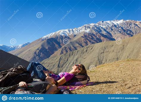 Two Young Girls Lying On Arid Ground By Andes Snowy Mountain Range
