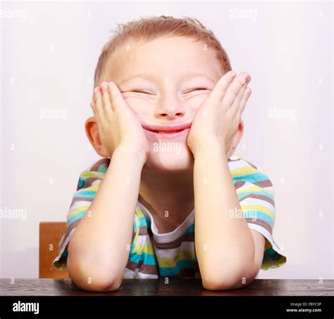 Portrait Of Blond Boy Child Kid Making Funny Face At The Table Stock