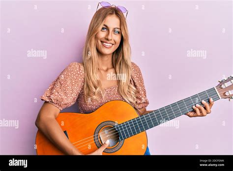 Beautiful Blonde Young Woman Playing Classical Guitar Smiling With A