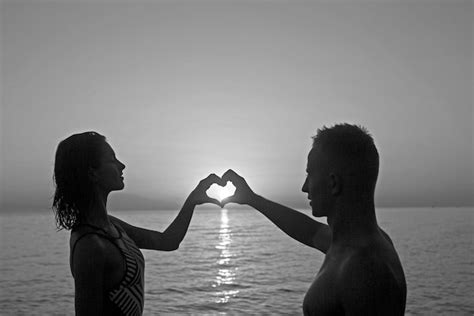 premium photo woman and man with heart hands at sea water in sunset summer holidays and travel