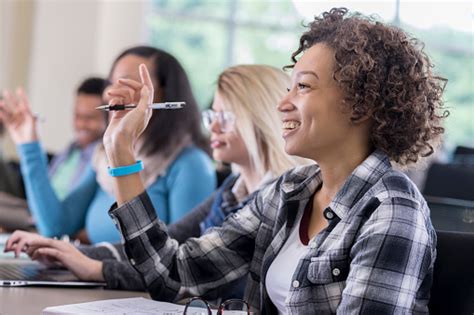 Confident Female College Students Raise Hands In Class Stock Photo