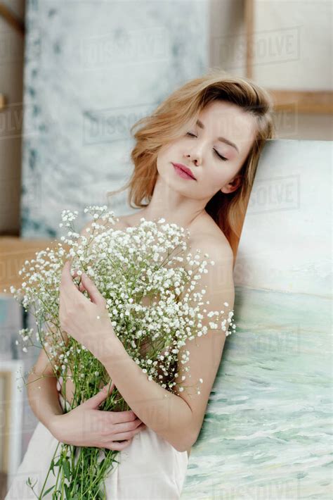 Sensual Naked Girl With Closed Eyes Holding White Flowers And Leaning