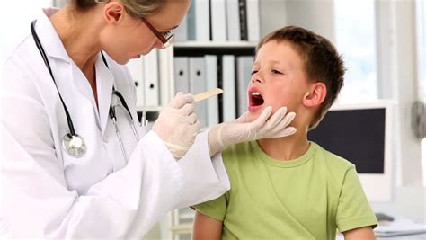 Doctor Checking Little Boys Tonsils In Her Office At The Hospital Stock