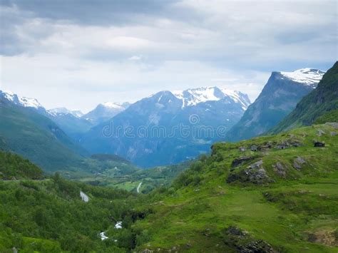 Mountain Landscape With Snow On Peaks And A Green Valley Near Geiranger