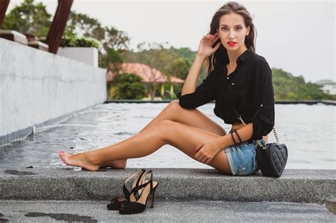 jeune sexy belle femme assise à la piscine pieds nus longues jambes bronzées maigres