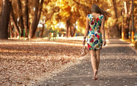 Woman Wearing Floral Dress Walking In Gray Pavement Road In Between