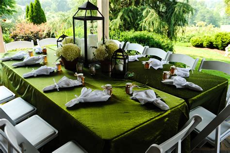 A Green Table With White Chairs And Candles On It