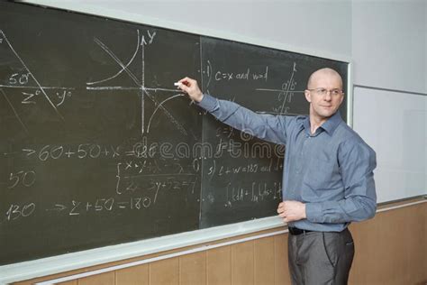 Confident Mature Professor Standing In Front Of Blackboard In Lecture