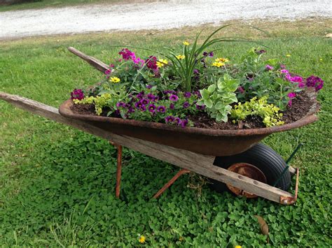 A Wheelbarrow Filled With Flowers In The Grass
