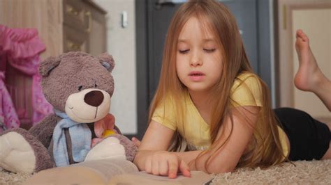 Cute Happy Little Girl With Teddy Bear And Reading Book