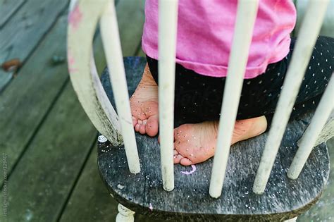 Girl With Glittery Feet Kneeling On Chair By Jess Lewis Stocksy United