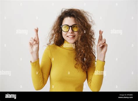 Excited Woman In Yellow Sweater Keeping Fingers Crossed Mouth Wide