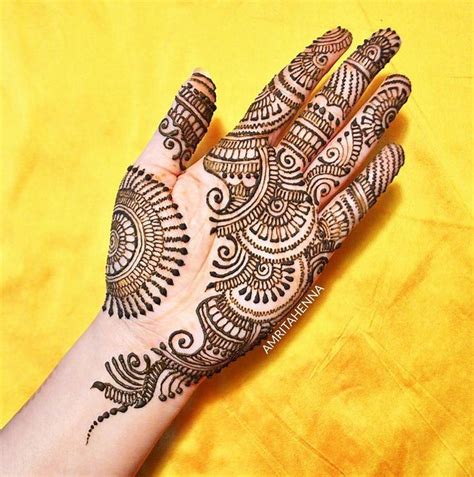 A Womans Hand With Henna Tattoos On It And Yellow Fabric In The Background