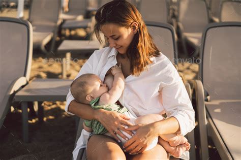 Newborn Baby Boy Sucking Milk From Mothers Breast On The Beach Stock