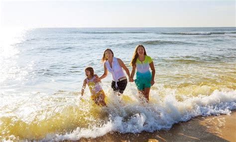 Familia Feliz Con El Bebé Caminando En La Playa Y Mirando El Mar Foto