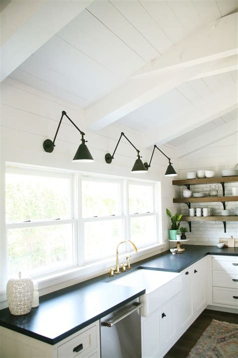 Taupe kitchen island, storage, and cabinets exude the elegance. Black and White Kitchen. Black sconces. Farmhouse sink. | Kitchen lighting design, Black sconces ...