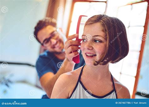 dad makes the prettiest hairstyles a father combing his little daughters hair at home stock