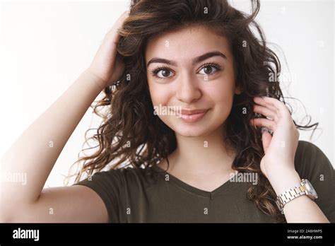close up cute slightly nervous armenian girl curly hairstyle checking haircut fixing curls near