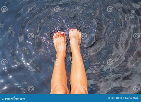 female bare feet in clean water woman is splashing water with her feet in lake stock image