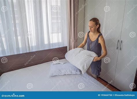 Young Female Housekeeper Changing Bedding In Hotel Room Stock Photo