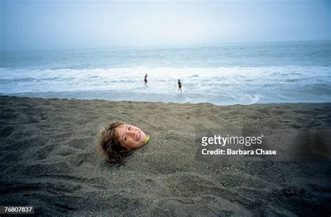 Caucasian Girl Buried In The Sand On Beach Photos And Premium High Res