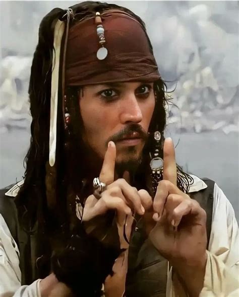 A Man Dressed As Captain Jack Sparrow Holding Two Fingers Up To The