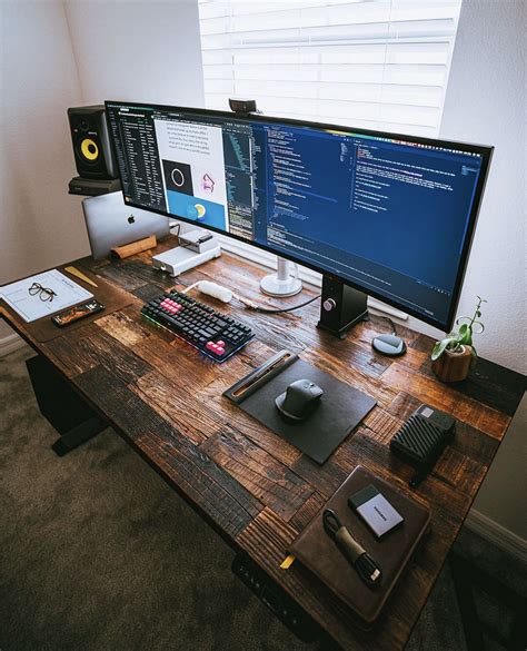 Two Computer Monitors Sitting On Top Of A Wooden Desk Next To A