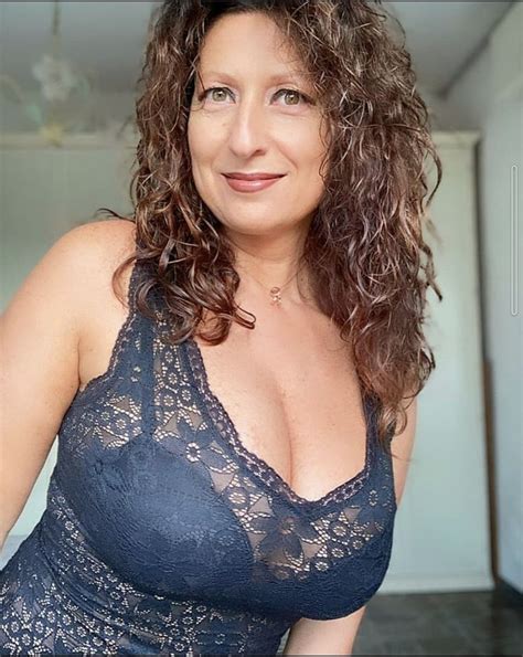 A Woman With Curly Hair Wearing A Blue Bra And Posing For The Camera In Front Of A Mirror