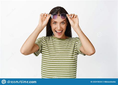 image of happy brunette woman take off sunglasses and looking excited at camera checking out