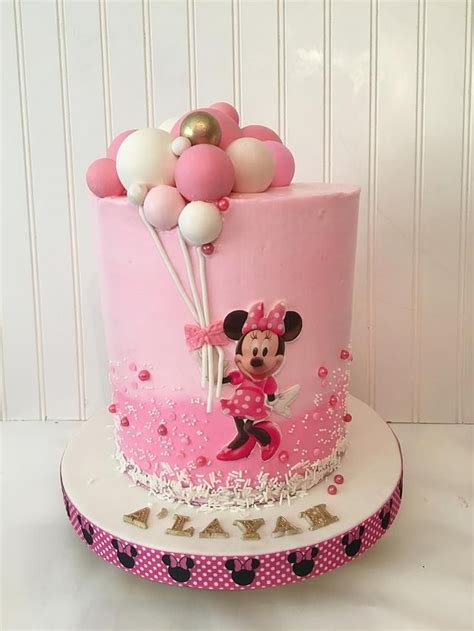 A Pink And White Cake With Minnie Mouse On It S Side Topped With Balloons