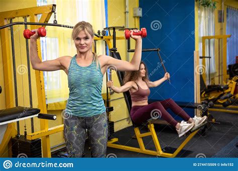 Two Young Women Exercising In A Gym Using Professional Equipment Stock