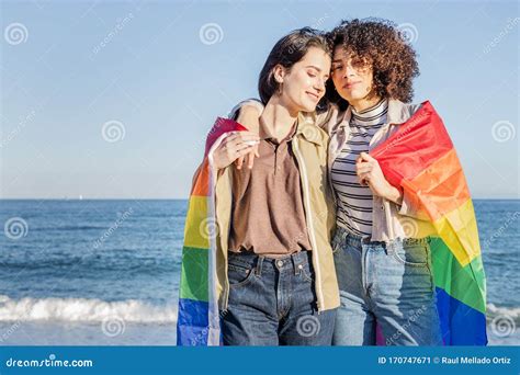 lesbian couple embracing wrapped in a rainbow flag stock image image of hispanic gender