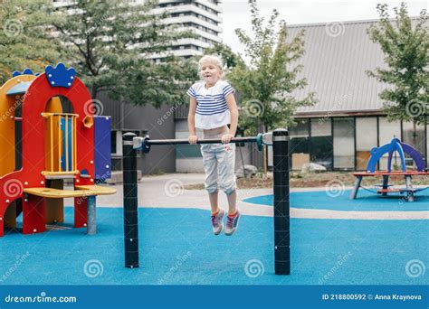 Happy Smiling Young Girl Exercising On Children Pull Ups Bar Outdoor At