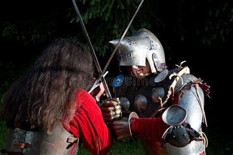 Two Knights Fighting With Swords In The Woods At Night Stock Photo