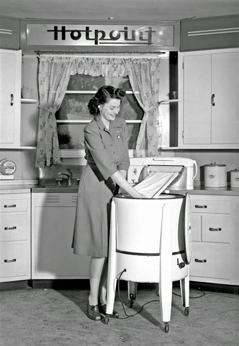 a woman demonstrates a hotpoint wringer washing machine 1943 vintage 1940s kitchen