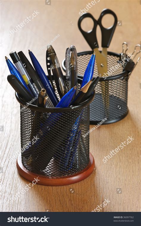 Pens Pencils And Scissors In Black Metal Containers On Wooden Desk