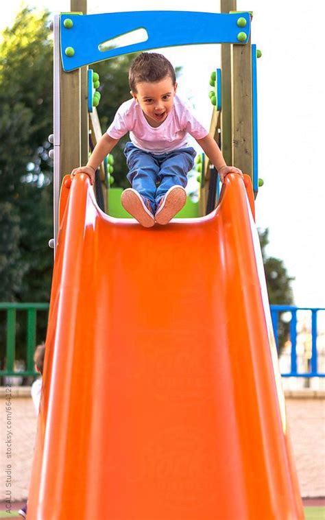 Child Sliding Down A Slide In A Playground By Acalu Studio Playground