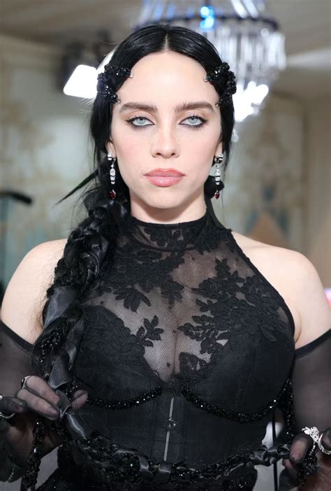 A Woman With Long Black Hair Wearing A Sheer Top And Holding Something