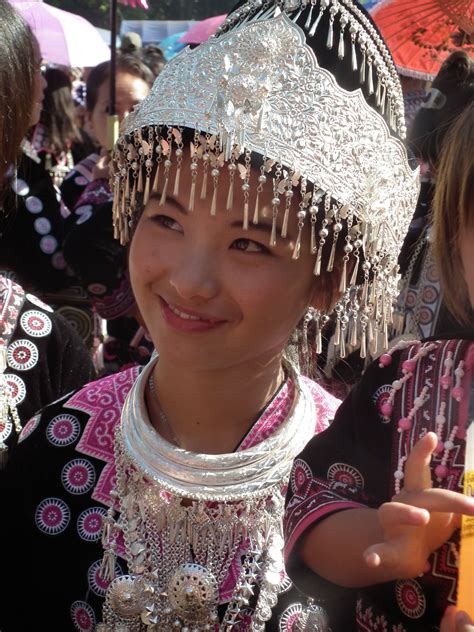 A young Hmong girl smiles in the morning sun. Her elaborate headdress ...