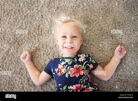 A Happy Little Girl Child In A Flower Dress Is Laying On Her Home