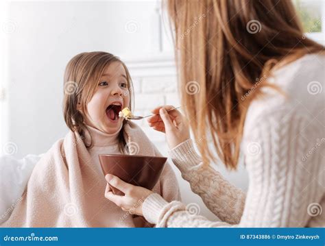 Positive Little Girl Enjoying Her Breakfast With The Mother Stock Photo