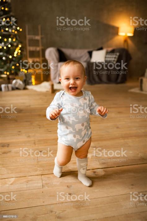 Little Baby Boy Laughs Cheerfully And Walks On Plank Floor Stock Photo