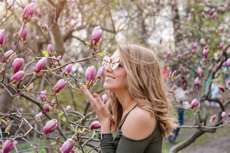 Young Blonde Woman Near Blossoming Magnolia Flowers Tree In Spring Park On Sunny Day Magnolia