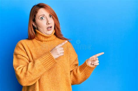 Beautiful Redhead Woman Pointing Fingers To The Side In Shock Face