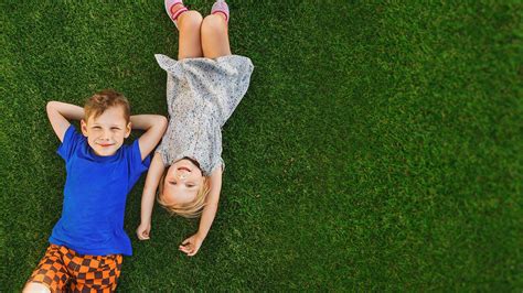 Children Lying On The Green Grass In The Park The Interaction O