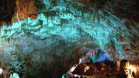 The Inside Of A Cave With Green And Blue Lights On Its Walls
