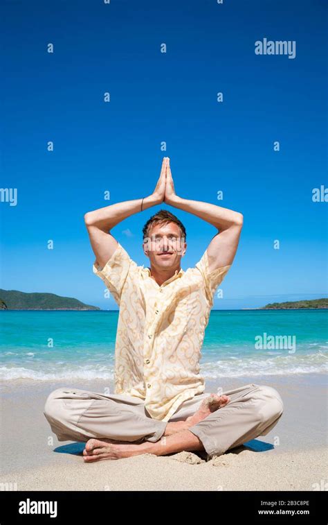 Smiling Man Sitting In Easy Yoga Pose With Namaste Hands Overhead At