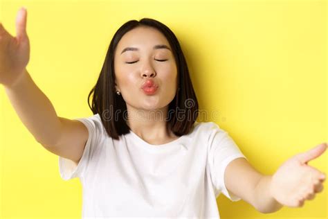 close up of cute asian woman stretch out hands to hold smartphone camera pucker lips and taking